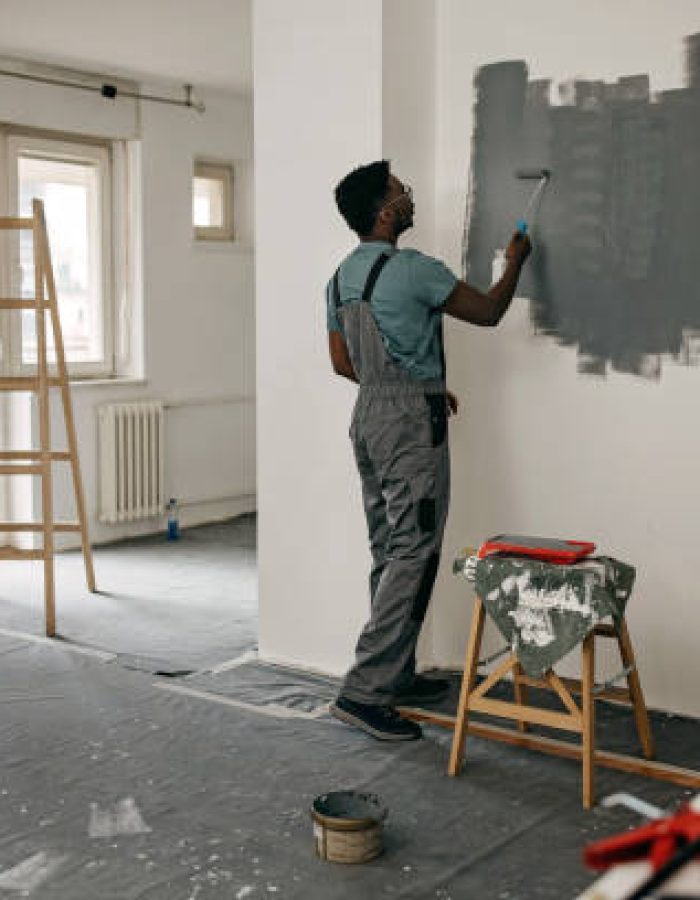African-American professional painter paints the wall indoors